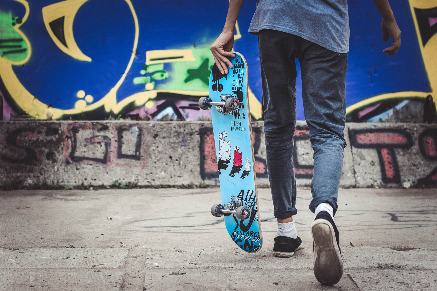 Joven con un monopatín en una zona urbana con grafiti, simbolizando la cultura del skate y el estilo de vida activo de los jóvenes en Tres Cantos.