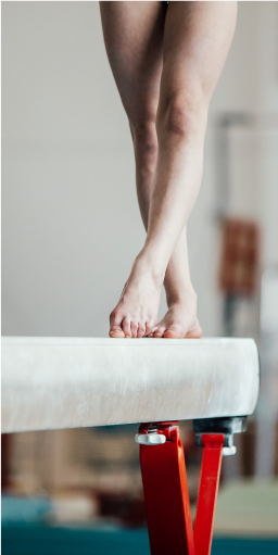 Primer plano de los pies de un gimnasta sobre la viga de equilibrio, ilustrando el enfoque y la precisión requeridos, aspectos trabajados también en la psicología deportiva en Tres Cantos.