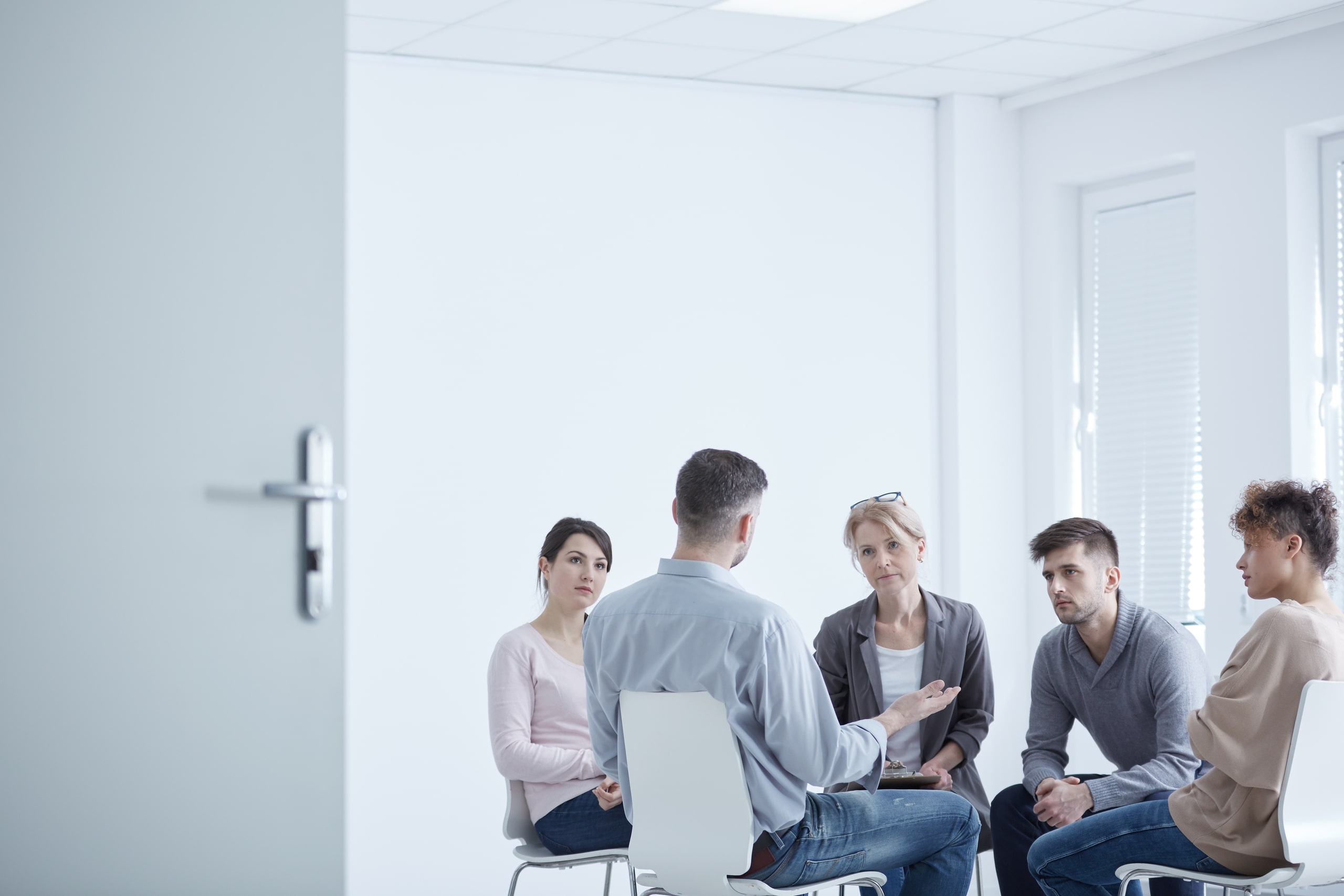 Grupo de personas participando en una sesión de terapia grupal en un entorno iluminado, enfocado en el tratamiento del trastorno por estrés postraumático (TEPT) mediante apoyo psicológico colectivo.